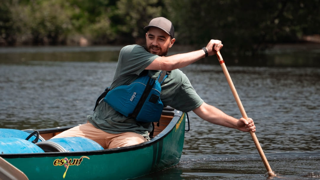 Jeune homme pagayant sur la rivière Saint-Charles dans un canot
